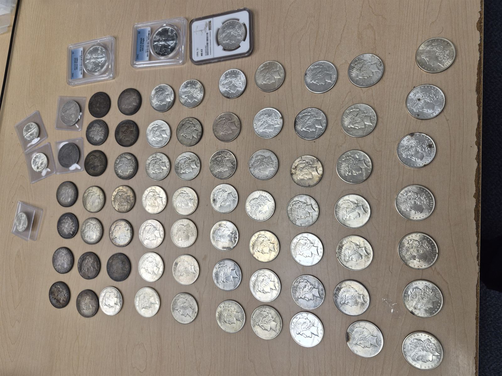 A detailed spread of Morgan and Peace silver dollars including graded NGC and PCGS examples